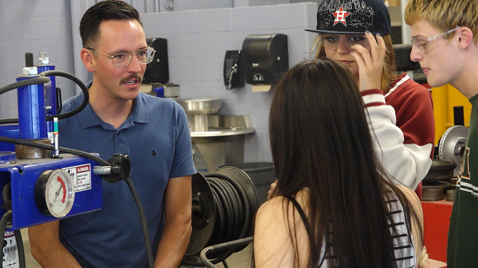 Trade school teacher talks with students